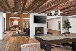 A modern living room with a pool table, a fireplace, and a television. - Riverfront Knoxville Suite - Neyland Stadium Views - Pool + Parking (Knoxville)