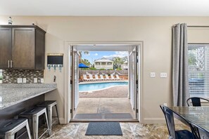 A kitchen with a view of a pool and a house in the background. - Ocean Kiss'D: Steps to Beach, Private Heated Pool, Free Golf Cart, Game Room (Destin)