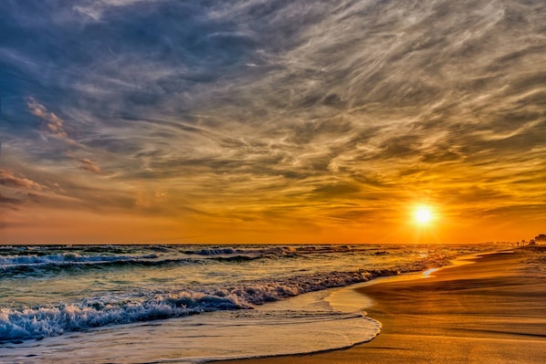 Ein Strand mit Wellen und einem Sonnenuntergang.