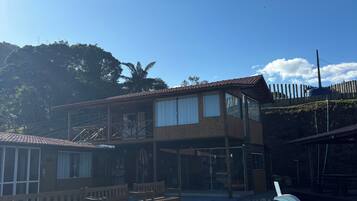 A wooden deck with a swimming pool, a two-story building with large windows, and a wooden fence.