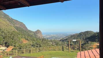 A pool area with a wooden deck, a bench, and a view of a mountainous landscape.