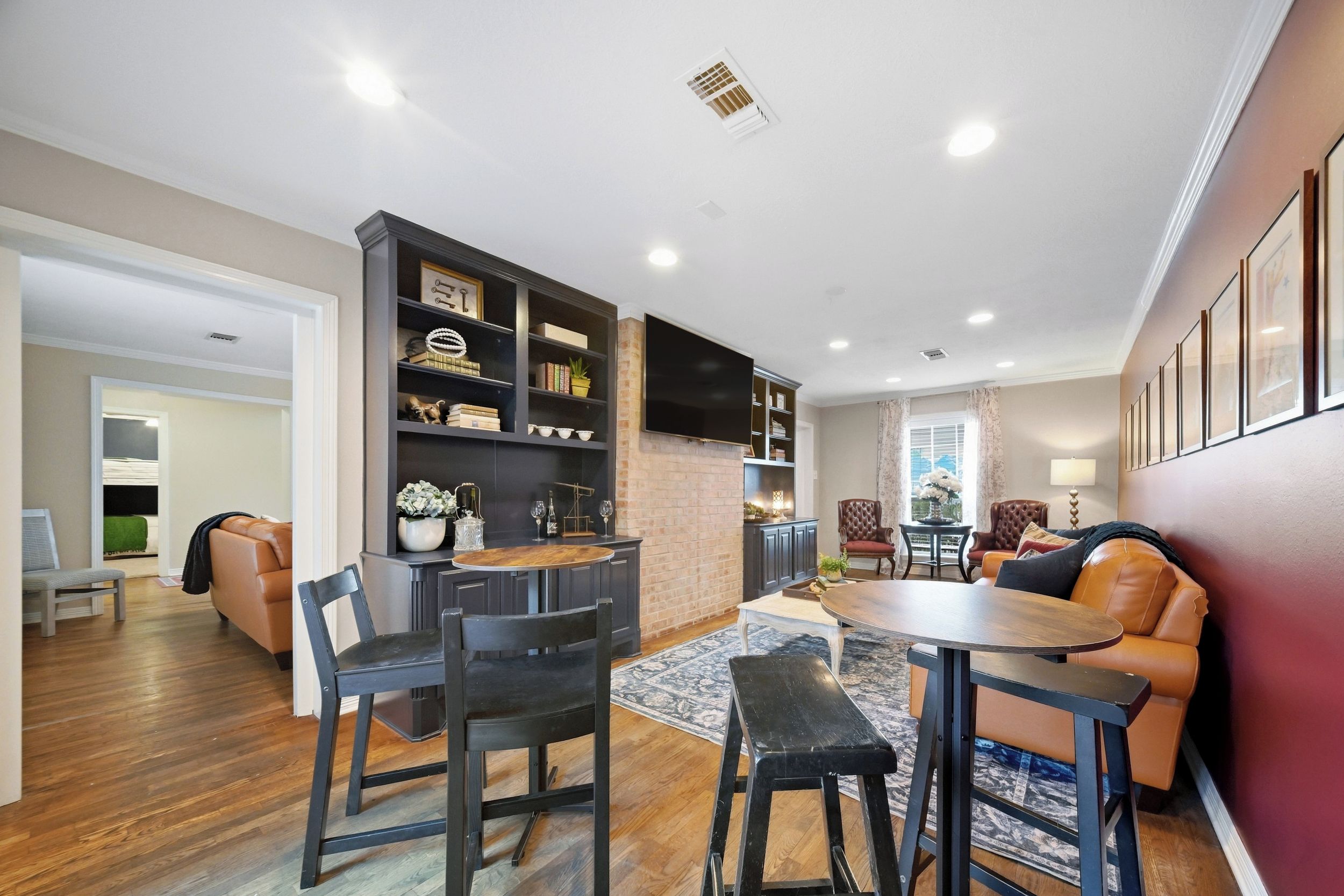 A modern living room with a fireplace, a dining area with a round table and chairs, and a seating area with a sofa and armchairs.