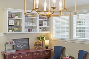 A room with a chandelier, a bookshelf with motivational quotes, a coffee bar, and a window with blinds. - Reveille Roundabout: An Aggie Gathering Place 5 min from Kyle Field Sleeps 27 (Bryan)