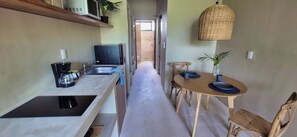 A narrow hallway leading to a dining area with a table and chairs, a coffee maker, and a hanging light fixture. - Relax in a Quiet and Cozy Loft in Cancún (cancun)