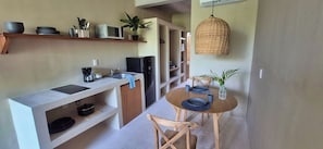 A compact kitchen with a microwave, coffee maker, and a small refrigerator. There is a dining area with a table set for two and a hanging light fixture. - Relax in a Quiet and Cozy Loft in Cancún (cancun)