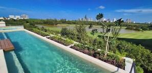 A swimming pool with a view of a golf course and city skyline. - Relax in a Quiet and Cozy Loft in Cancún (cancun)