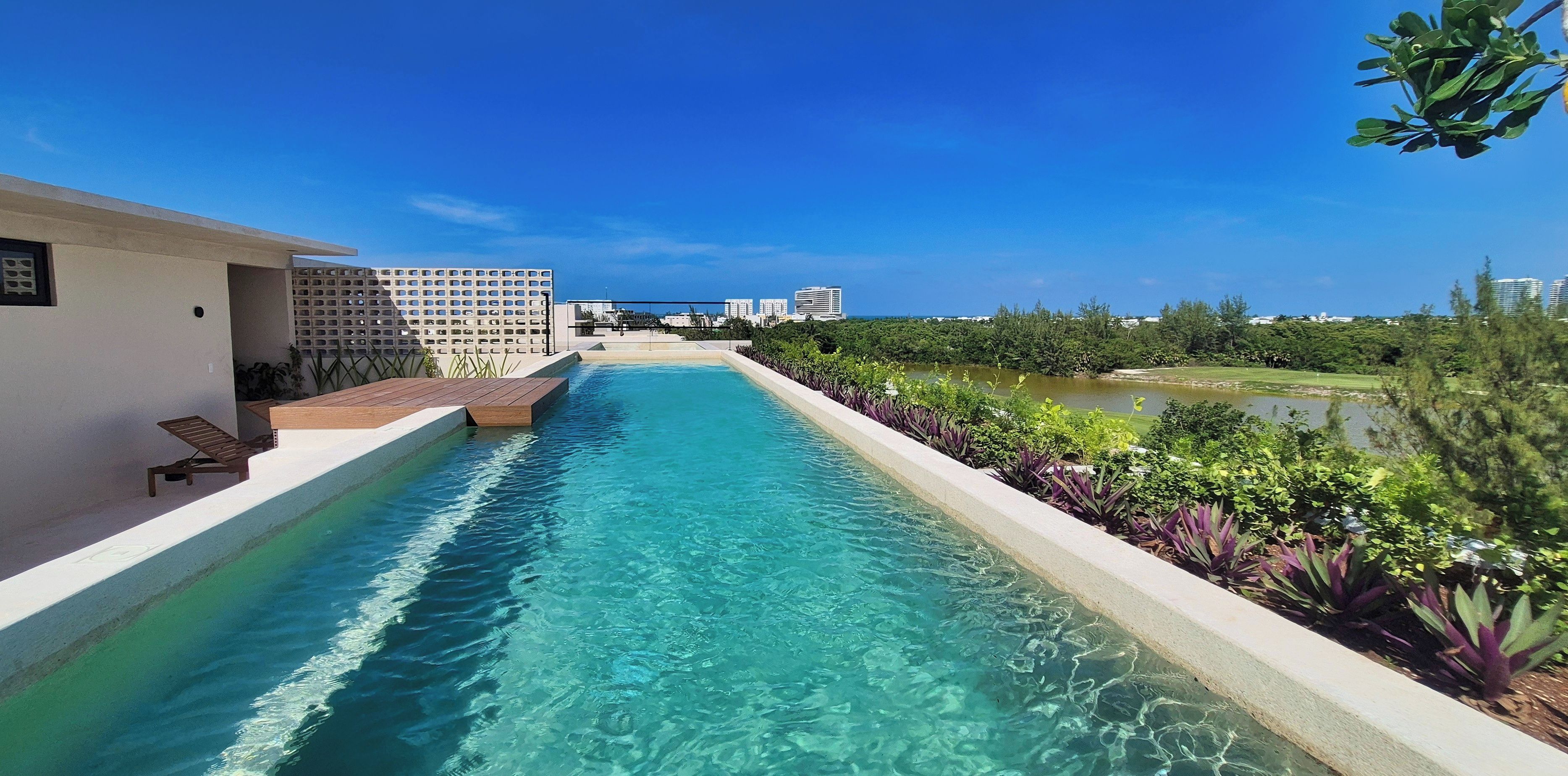 A clear swimming pool with a view of a cityscape in the background.