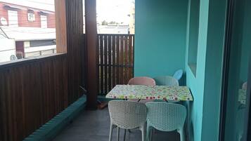 A balcony with a table and chairs, a wooden fence, and a view of buildings.