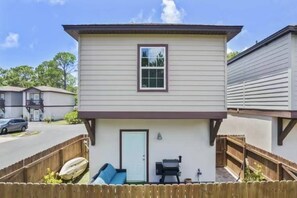 A two-story building with a front door, a small porch area, and a barbecue grill. - Cozy 3-bedroom house 5 min drive to the beach (Panama City Beach)