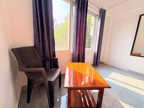 Una habitación con una mesa de madera y dos sillas, una ventana con cortinas y un espejo en la pared.
