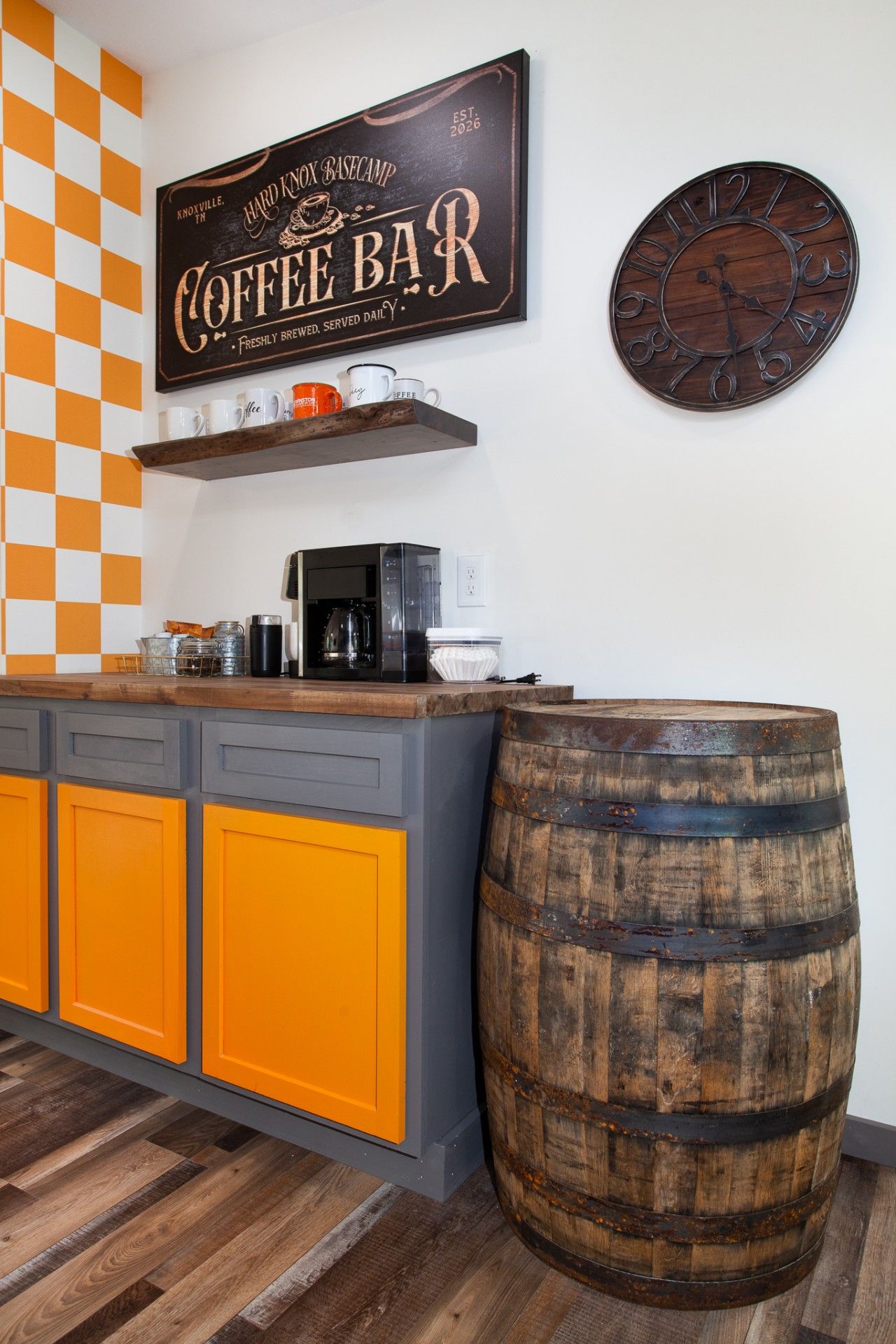 A kitchen area with a coffee bar, a clock, and a large wooden barrel.