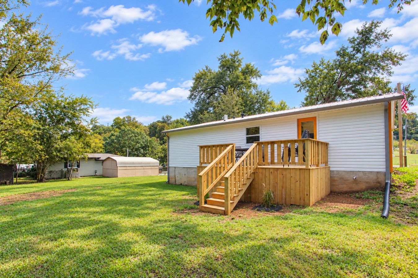 A single-story mobile home with a wooden deck and a small porch.