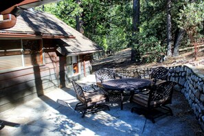 A wooden cabin with a patio area featuring a table and chairs. - Cozy Cabin! Short Walk to Town Center! Deck! Patio! Hammock! Fireplace! (Idyllwild-Pine Cove)