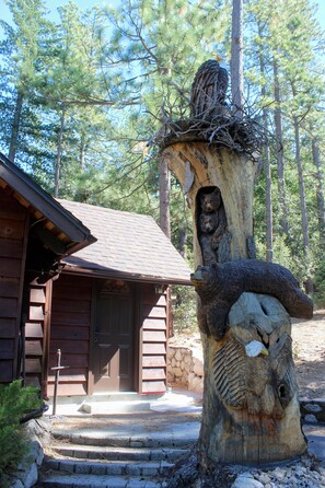 A rustic cabin with a wooden exterior, a stone foundation, and a front porch leading to a door. - Cozy Cabin! Short Walk to Town Center! Deck! Patio! Hammock! Fireplace! (Idyllwild-Pine Cove)