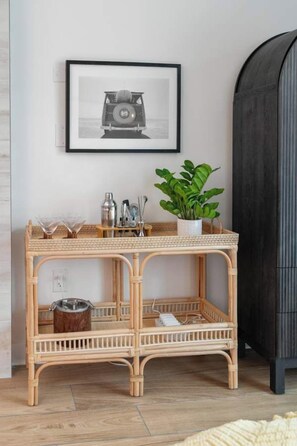 A wicker console table with a potted plant, a framed picture, and bar tools. - Oceanfront Pierlight Studio w/VR & Minibar at Yachtsman S1103 (Myrtle Beach)