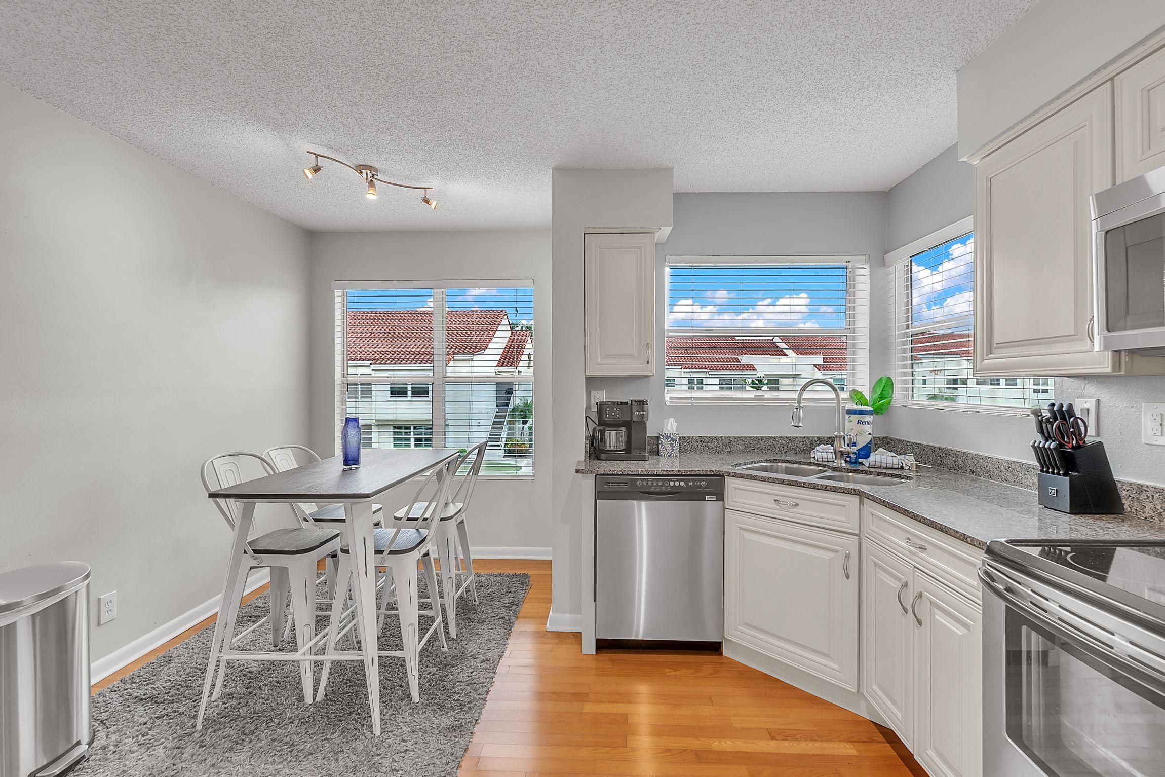 A modern kitchen with white cabinetry, a stainless steel dishwasher, and a built-in oven.