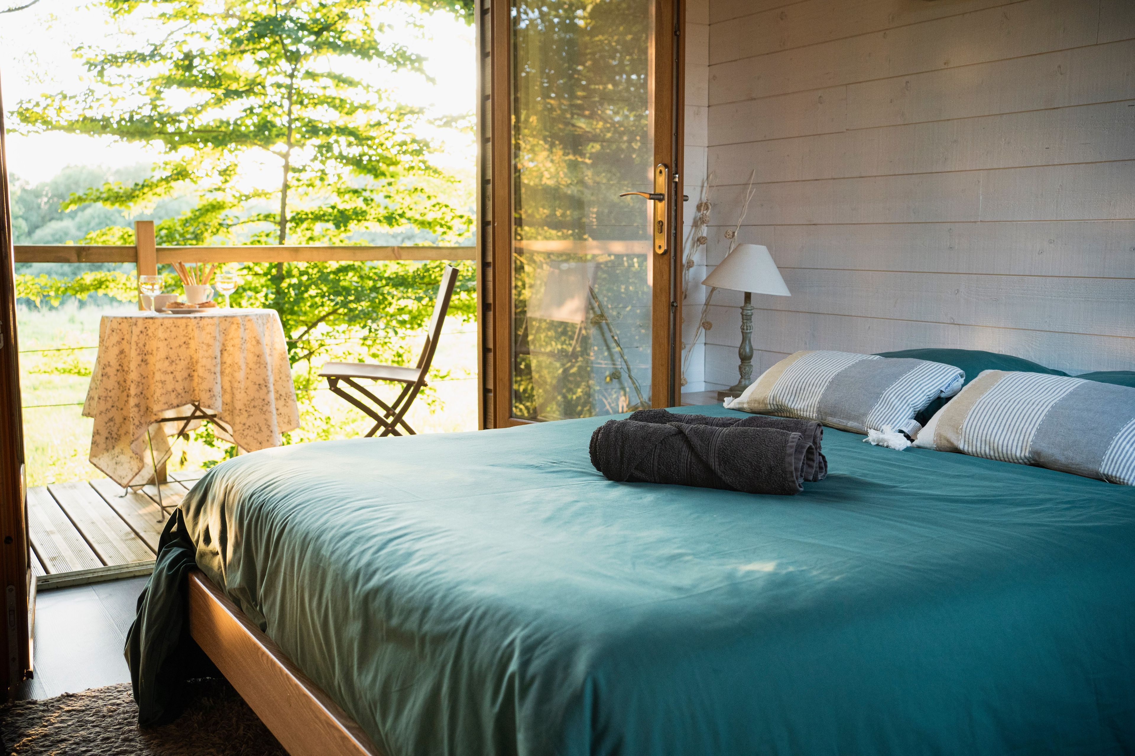 Un dormitorio con cama, una mesa y una silla, y vistas a zonas verdes.