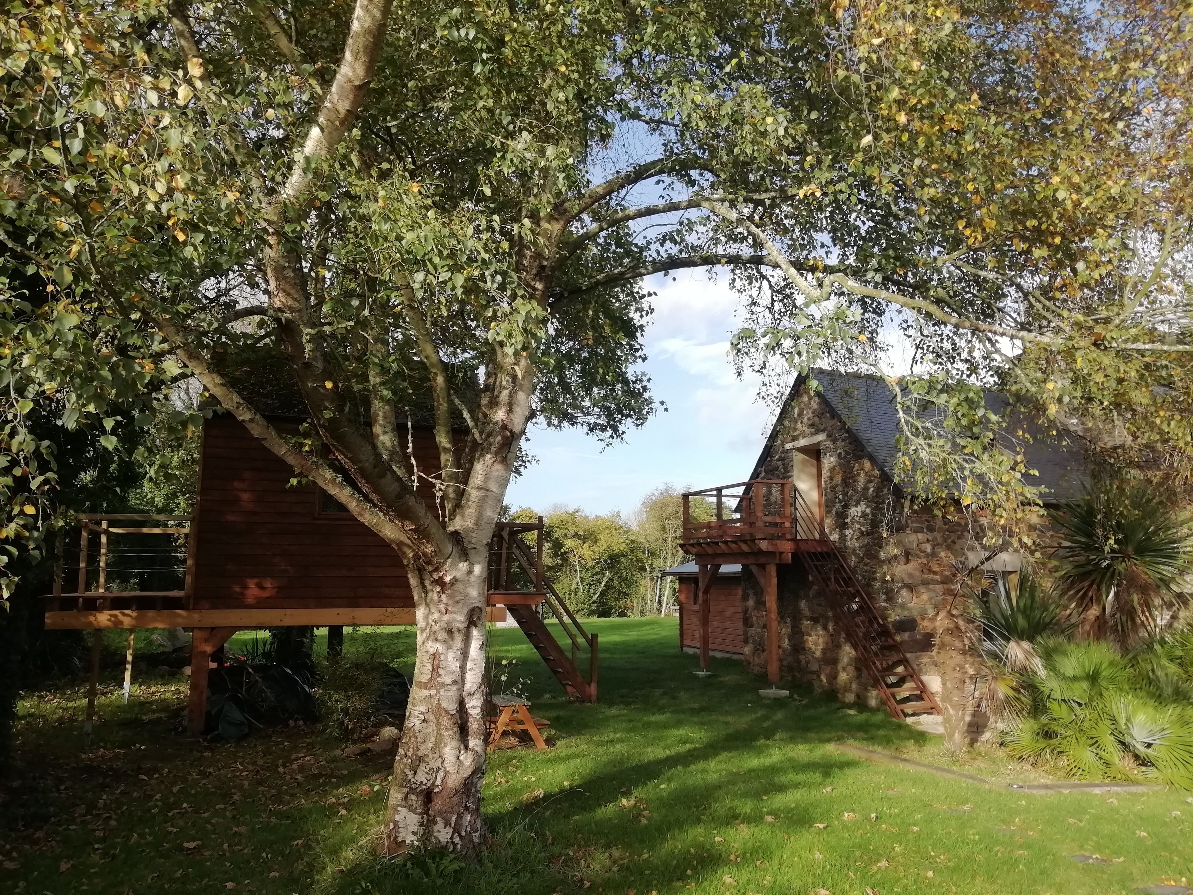 A rustic cabin with a wooden deck and a stone wall.