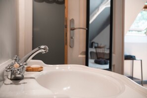 A bathroom with a modern sink, a glass shower door, and a view of a staircase leading to a balcony. - Guest Room 'La Corzic' (Pléguien)
