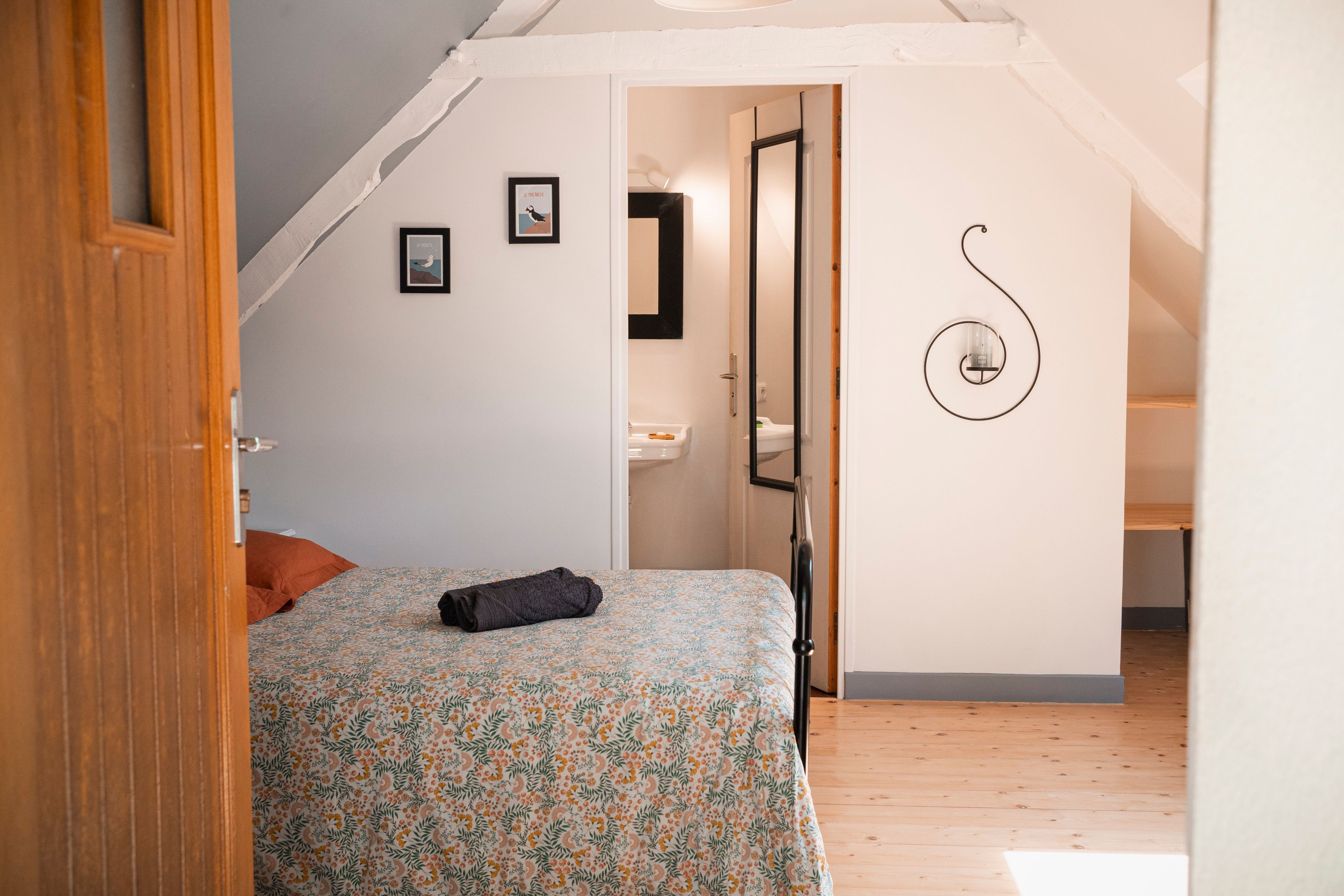 Une chambre à coucher avec un lit, une petite fenêtre et une porte donnant sur une salle de bain.