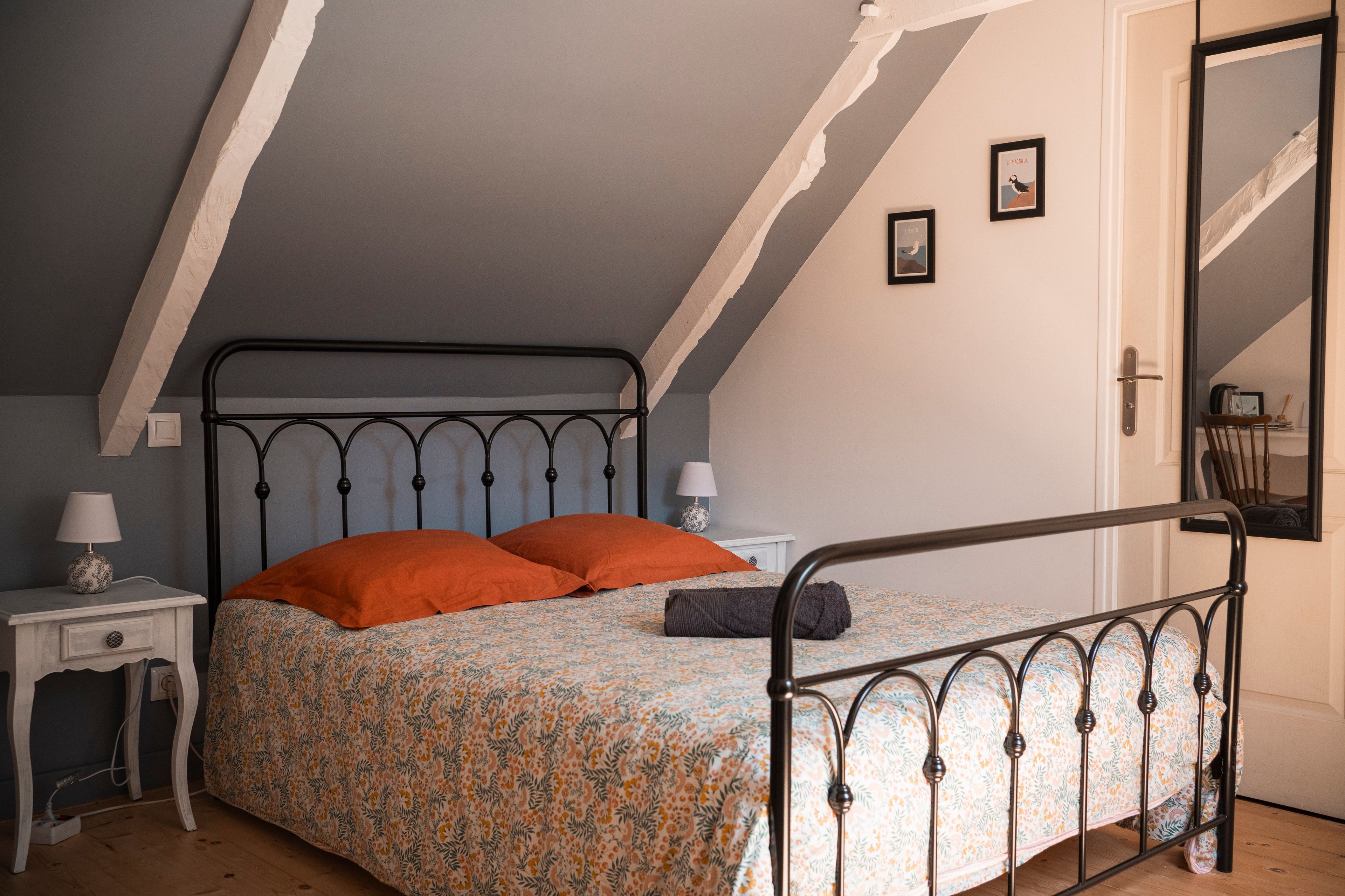 Ein Schlafzimmer mit einem Bett, einem Nachttisch, einer Lampe und einem gerahmten Bild an der Wand.