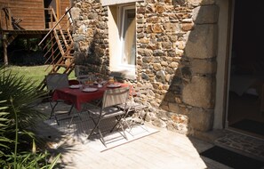 A stone building with a dining area set up outside. - Guest Room 'La Kerguidoué' (Pléguien)