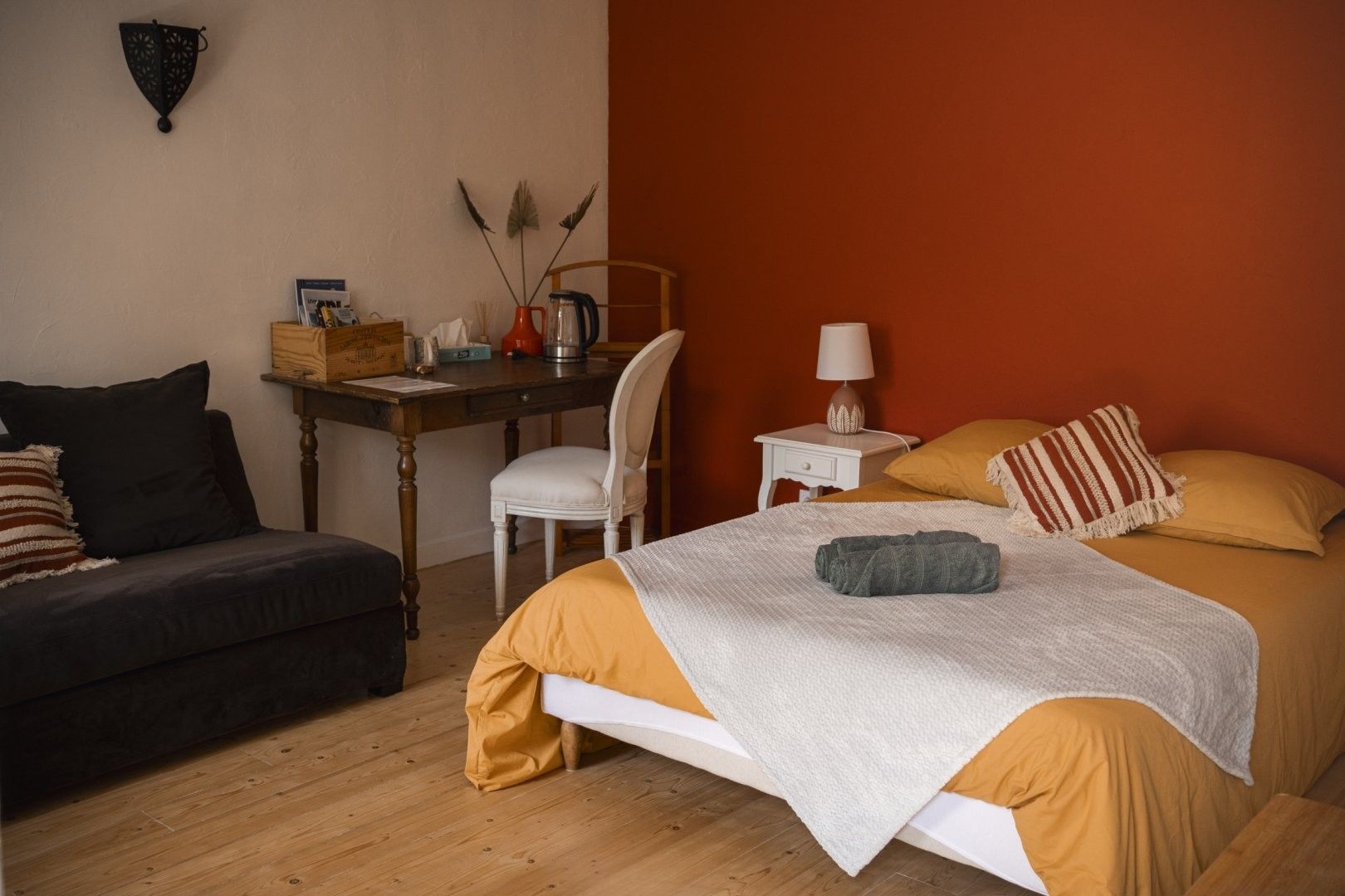 Een slaapkamer met een bed, bureau, stoel en nachtkastje.