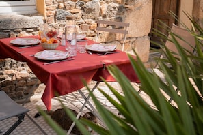 Taula de menjador a l'aire lliure preparada amb plats, coberts, gots i un bol de fruita.