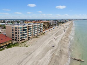 A beachfront hotel with multiple floors, a sandy beach, and a clear view of the ocean. - Madeira Vista 306 (Madeira Beach)