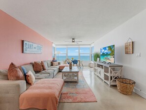 A living room with a large window, a sofa, a coffee table, and a TV. - Madeira Vista 306 (Madeira Beach)