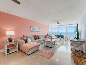A living room with a sofa, coffee table, and a view of the ocean. - Madeira Vista 306 (Madeira Beach)