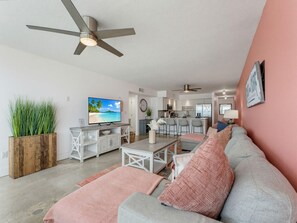A modern living room with a grey sofa, a television, and a ceiling fan. - Madeira Vista 306 (Madeira Beach)