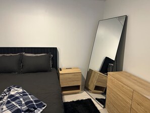 Una camera da letto con un letto, un comodino, una cassettiera e uno specchio grande.