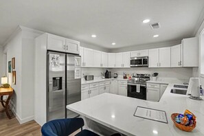 A modern kitchen with white cabinetry, stainless steel appliances, and a marble countertop. - Brand-New 4BR/3BA Home on Dayton’s West Side (Trotwood)