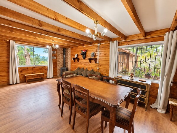 A wooden interior with a dining table, chairs, a sofa, and a fireplace. - Cabaña del Bosque - Laguna Verde (Valparaiso)