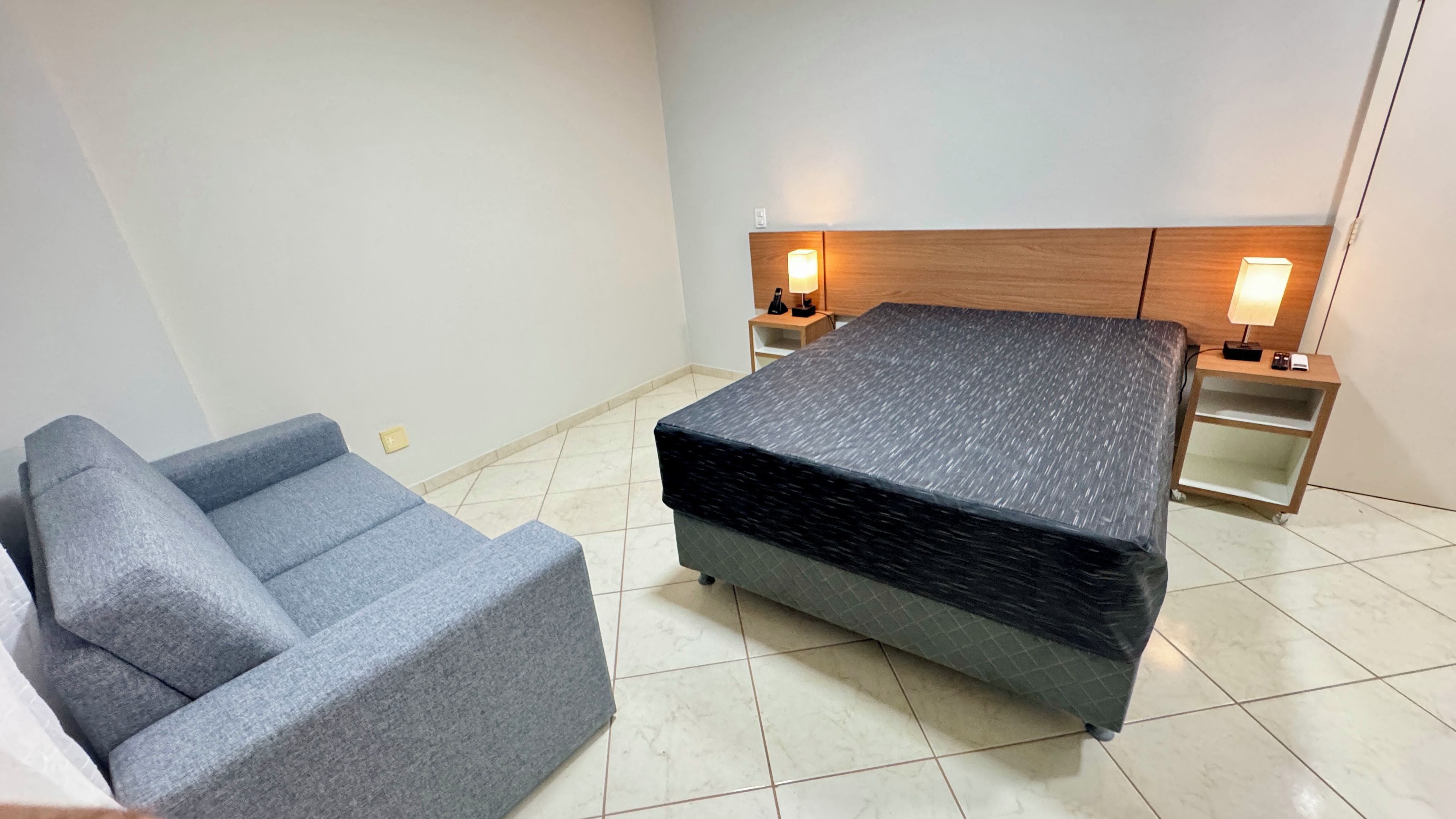 Ein Schlafzimmer mit einem Bett, einem Nachttisch, einer Lampe, einem Stuhl und einem Beistelltisch.