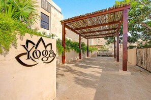 A yoga studio entrance with a pergola, a sign, and a pathway leading to a building. - Gran Haven | Prv Hot Tub + Pool | 5 Min to Beach (Tulum)