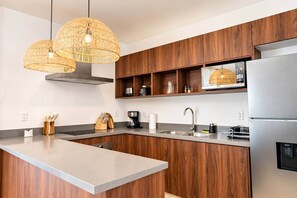 Eine moderne Küche mit einer zentralen Kochinsel, Holzschränken, einer eingebauten Mikrowelle und einem Edelstahlkühlschrank.