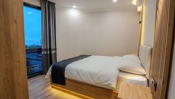 Une chambre d’hôtel moderne avec un lit, une vue sur l’extérieur et une tête de lit en bois.