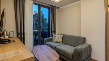Una habitación moderna con un escritorio de madera, un sofá gris y una ventana con cortinas.