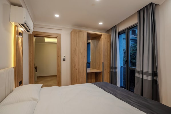 A modern bedroom with a bed, built-in wardrobe, and a window with curtains. - Zaya Residence (Yomra)