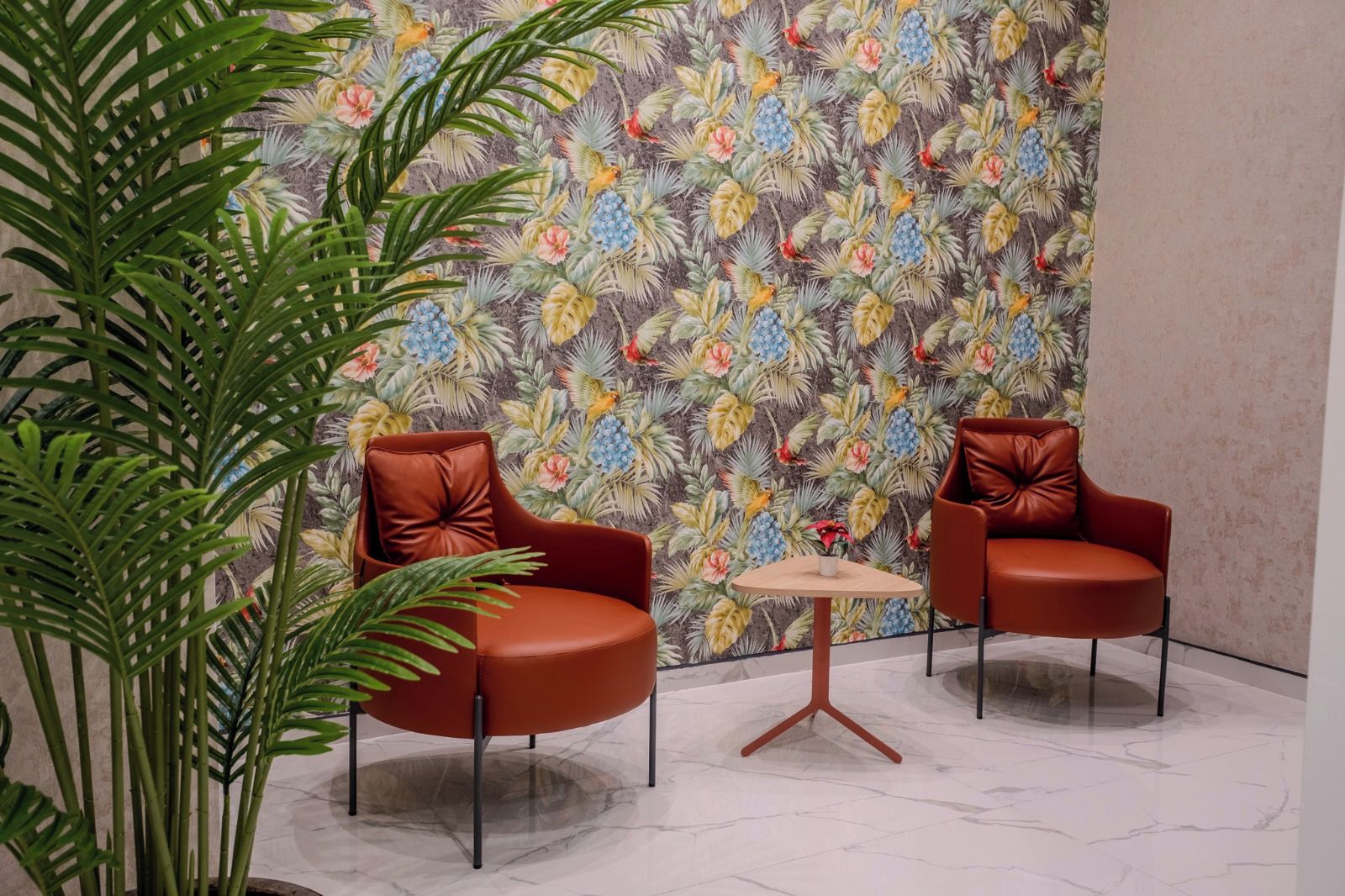Een kamer met twee leren fauteuils, een klein rond tafeltje en een grote kamerplant.