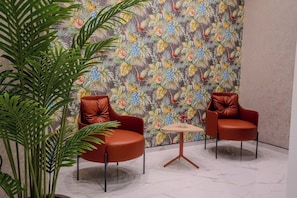 A room with two leather armchairs, a small round table, and a large potted plant. - Zaya Residence (Yomra)