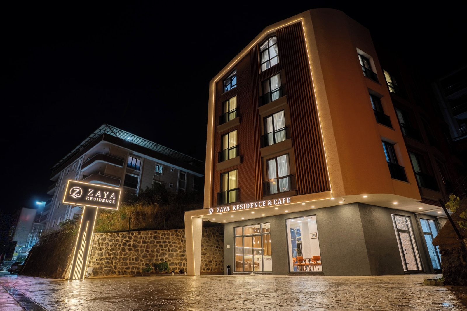 Un edificio a più piani con un cartello all'ingresso che riporta 'Zaya Residence & Cafe'.