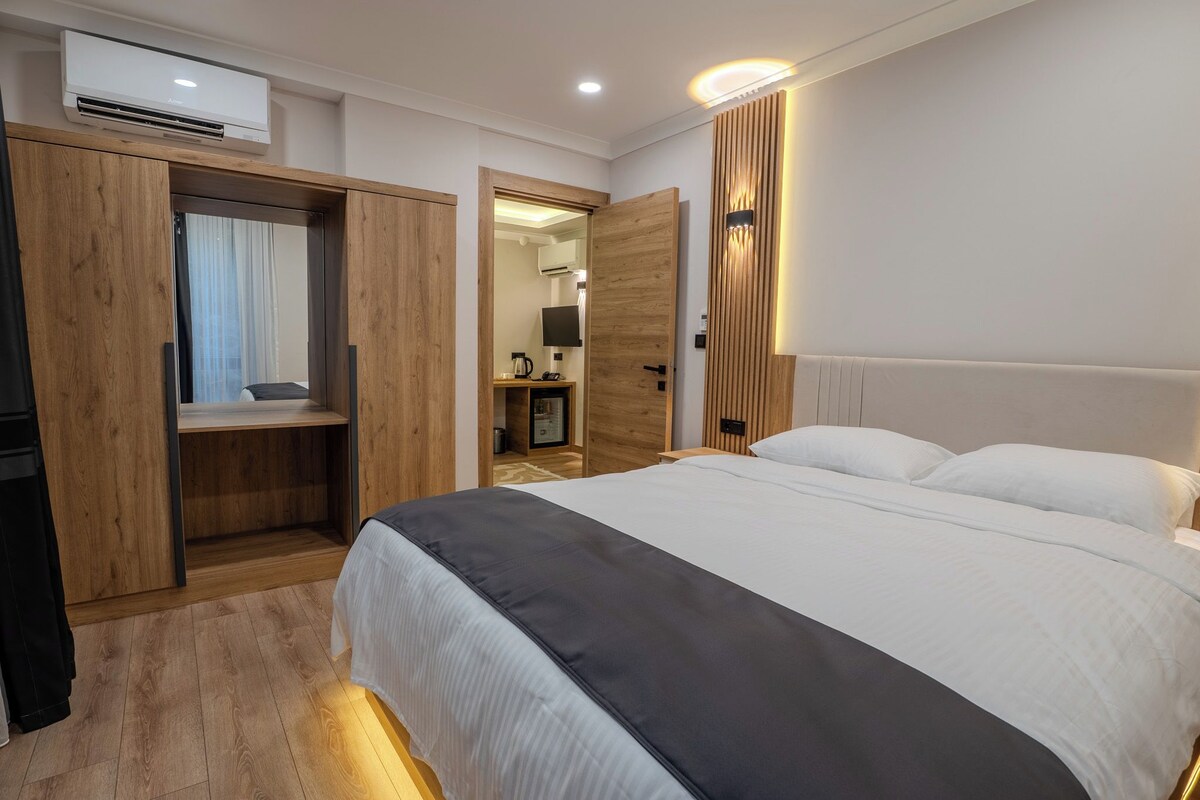 Habitació d'hotel amb llit, armari, escriptori i televisió.