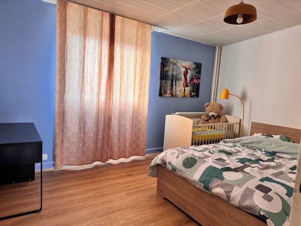 A bedroom with a bed, a crib, a teddy bear, a lamp, and a painting on the wall. - Right in the heart of Valence! 3-bedroom apartment, ideal for families and business trips (Valence)