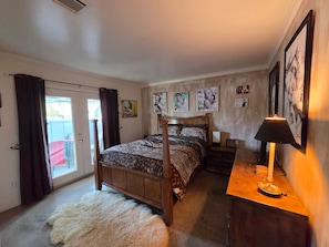 A bedroom with a double bed, a bedside table with a lamp, and a door leading to a balcony. - Casa De Eden, Gorgeous Mountain Views (Palm Springs)