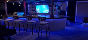 A bar area with a TV screen, bar stools, and blue ambient lighting. - Casa De Eden, Gorgeous Mountain Views (Palm Springs)