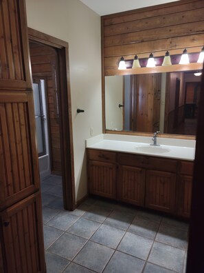A bathroom with wooden cabinets, a white sink, and a mirror with lights above it. - Spacious 4-bedroom house in charming Athens with AC (Athens)