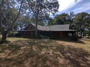 A rustic wooden cabin with a porch, surrounded by trees and a grassy yard. - Spacious 4-bedroom house in charming Athens with AC (Athens)
